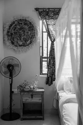 a bedroom with a bed and a window with a fan at White House Hostels - Arusha in Arusha