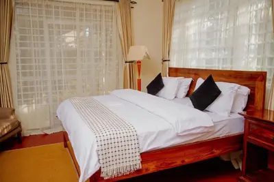 a bedroom with a bed with white sheets and a window at Protea House in Marombosa