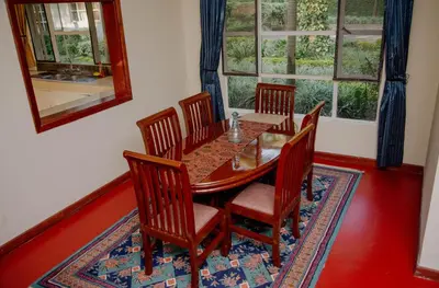 a dining room with a wooden table and chairs at Protea House in Marombosa