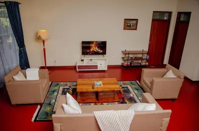 a living room with couches and a fire in the fireplace at Protea House in Marombosa
