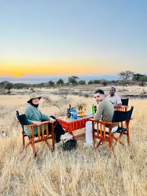 a group of people sitting around a table in a field at Furaha Luxury Lodge in Mto wa Mbu