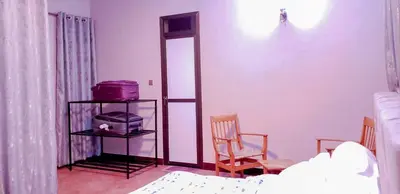 a bedroom with a bed and two chairs and a mirror at Given House in Tuvaila