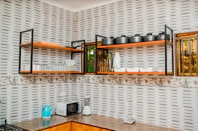 a kitchen with wooden shelves on a wall at Avek Home Stay Ngorongoro Room in Uru