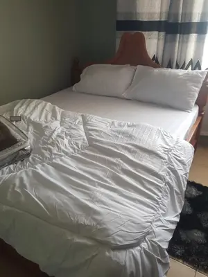 an unmade bed with white sheets and pillows at othman homes in Arusha