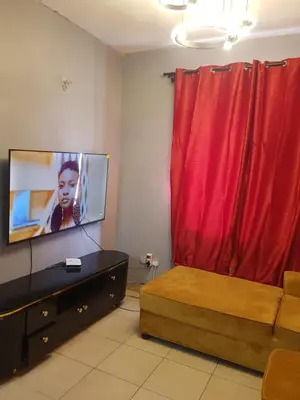 a living room with a tv and a red curtain at othman homes in Arusha