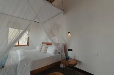 a bedroom with a white bed and a window at Foot On Africa Safari Lodge in Mto wa Mbu