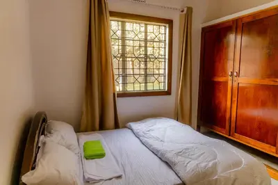 a bedroom with a bed and a dresser and a window at Arusha backpackers homes in Arusha