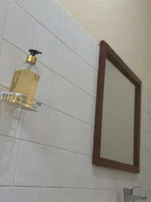 a bathroom with a mirror and a light on a wall at Arusha backpackers homes in Arusha