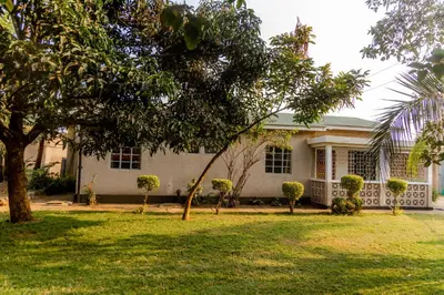 a white house with trees in front of it at Arusha backpackers homes in Arusha