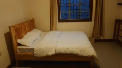 a bed with white sheets and a window in a bedroom at Arusha backpackers homes in Arusha