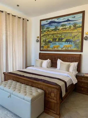 a bedroom with a large bed with a painting on the wall at Casa Laurensana in Arusha