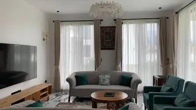 a living room with a couch and chairs and a tv at Casa Laurensana in Arusha