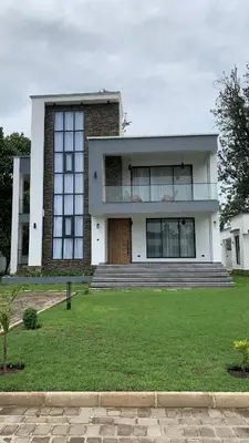a large white house with a door and some grass at Casa Laurensana in Arusha