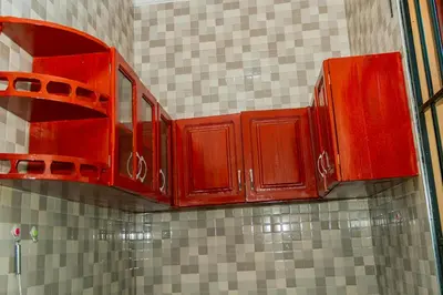 a kitchen with red cabinets on a tiled wall at Neylisa Apartments in Arusha