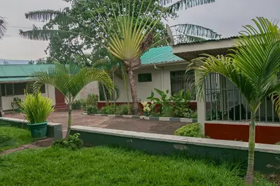 a house with palm trees in front of it at Moshi Green Lodge in Moshi