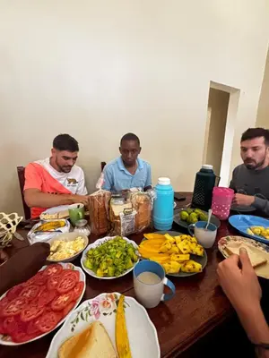 a group of men sitting around a table with food at Kinyaiya's Sereniry Farmstay