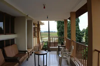 a balcony with tables and chairs and a view of a field at Kinyaiya's Sereniry Farmstay