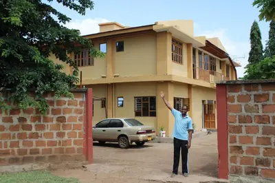 a man standing in front of a house at Kinyaiya's Sereniry Farmstay