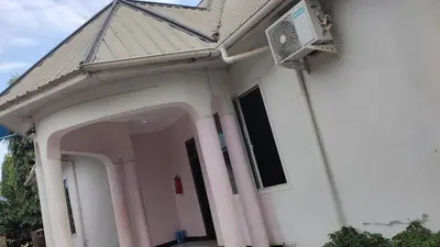 a white house with an archway and a fan at Hill Park Lodge Moshi in Shiri