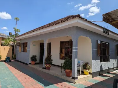 a small house with potted plants in front of it at Arusha Sunbird Lodge in Arusha