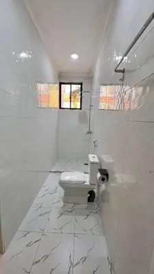 a white bathroom with a toilet and a window at Domin Homestay in Arusha