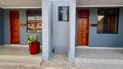 a red plant in a red pot in front of two doors at Domin Homestay in Arusha
