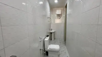 a white bathroom with a toilet and a sink at Domin Homestay in Arusha