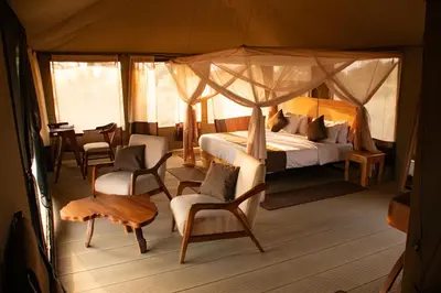 a bedroom with a bed and chairs in a tent at Tarangire Greenland Retreat in Kaiti
