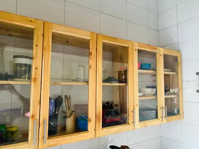 a wooden cabinet with glass doors in a kitchen at Blessings Home in Arusha