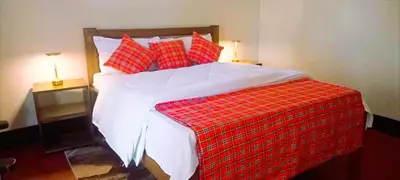 a red and white bed with red pillows on it at Africa Sky Lodge, Bar and Restaurant in Karatu