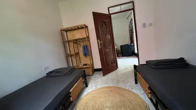 a room with two beds and a door with a mirror at Amoy River Lodge in Moshi