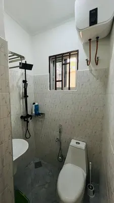 a bathroom with a toilet and a sink and a window at Amoy River Lodge in Moshi