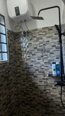 a bathroom with a shower with a stone wall at Amoy River Lodge in Moshi