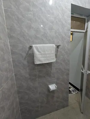 a bathroom with a shower with a towel on a wall at Utulivu Home Stay Apartment in Arusha