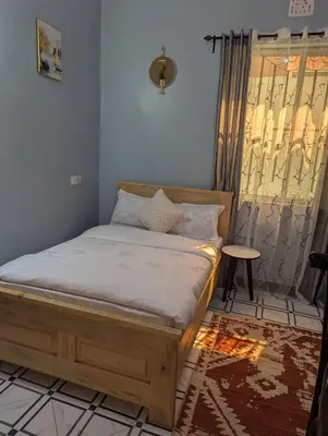 a bed sitting in a room with a window at Utulivu Home Stay Apartment in Arusha