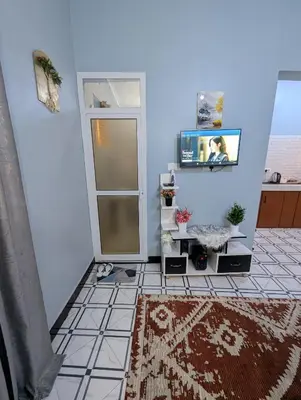 a living room with a tv and a tiled floor at Utulivu Home Stay Apartment in Arusha