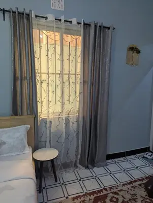 a bedroom with a bed and a window with curtains at Utulivu Home Stay Apartment in Arusha
