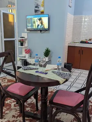 a table with two chairs and a television on a wall at Utulivu Home Stay Apartment in Arusha