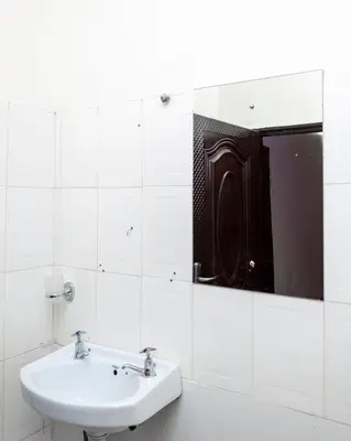 a white bathroom with a sink and a mirror at Richard's Road Homestay in Boma la Ngombe