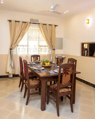a dining room with a wooden table and chairs at Richard's Road Homestay in Boma la Ngombe