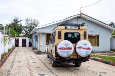 a van parked in front of a house with two tires at Richard's Road Homestay in Boma la Ngombe