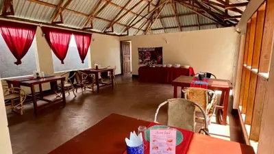 a room with tables and chairs and red curtains at Kwetu Villa in Arusha
