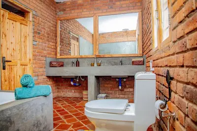 a brick bathroom with a toilet and a sink at Tranquil Hillhouse in Nkoanrua