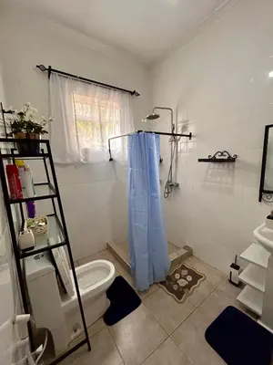 a bathroom with a toilet and a blue shower curtain at 1 Bedroom- Tranquil Meru Retreat in Nkoanrua