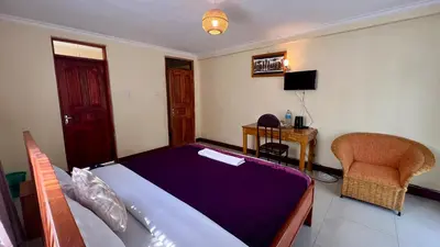 a bedroom with a bed and a desk and a chair at Runako Lodge in Arusha
