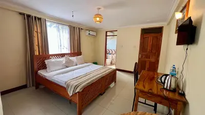 a bedroom with a bed and a desk and a television at Runako Lodge in Arusha