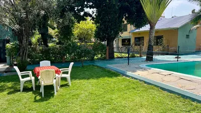 a table and chairs in a yard next to a pool at Runako Lodge in Arusha