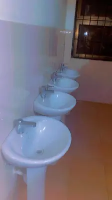 a row of white sinks in a bathroom at Kyanga Hostel in Arusha