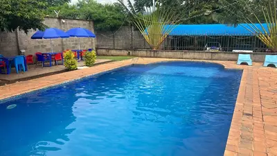 a large blue swimming pool with blue chairs and umbrellas at Lufo Heritage Farm - Octavian Mshiu Residence in Uru