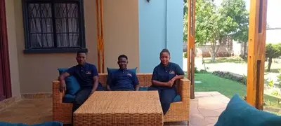 a group of three men sitting on wicker chairs at Lufo Heritage Farm - Octavian Mshiu Residence in Uru